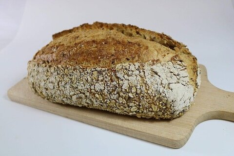 loaf of seeded bread on breadboard